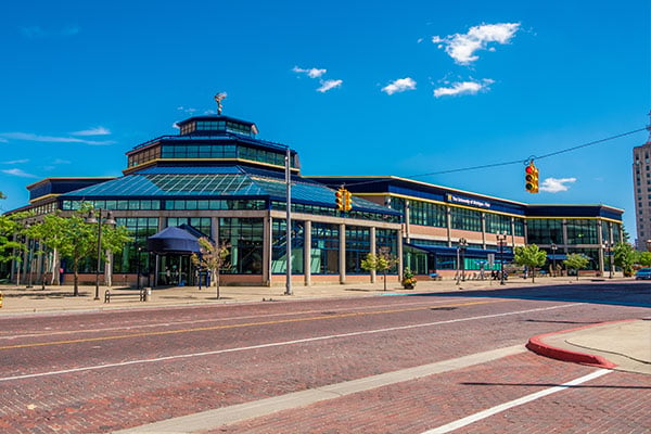 Exterior view of a large modern building with glass windows and a blue roof under a clear blue sky.