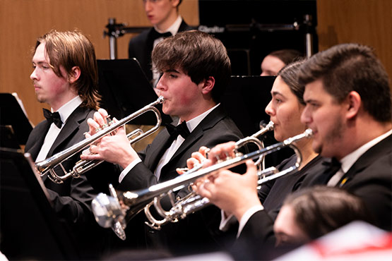 A group of musicians playing trumpets in formal attire during a performance.