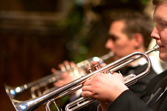 Two musicians playing silver trumpets in a performance setting.