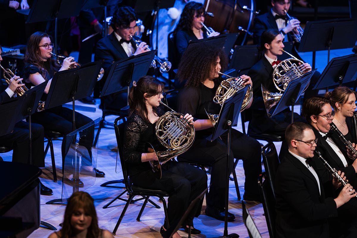 Student musicians perform on stage under theatrical lighting at The Whiting Auditorium.