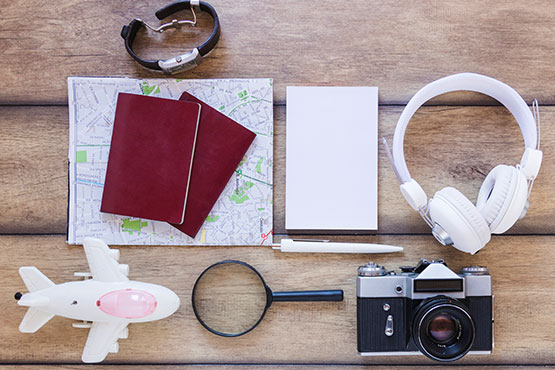 A travel-themed flat lay with passports, headphones, a camera, and a map on a wooden surface.