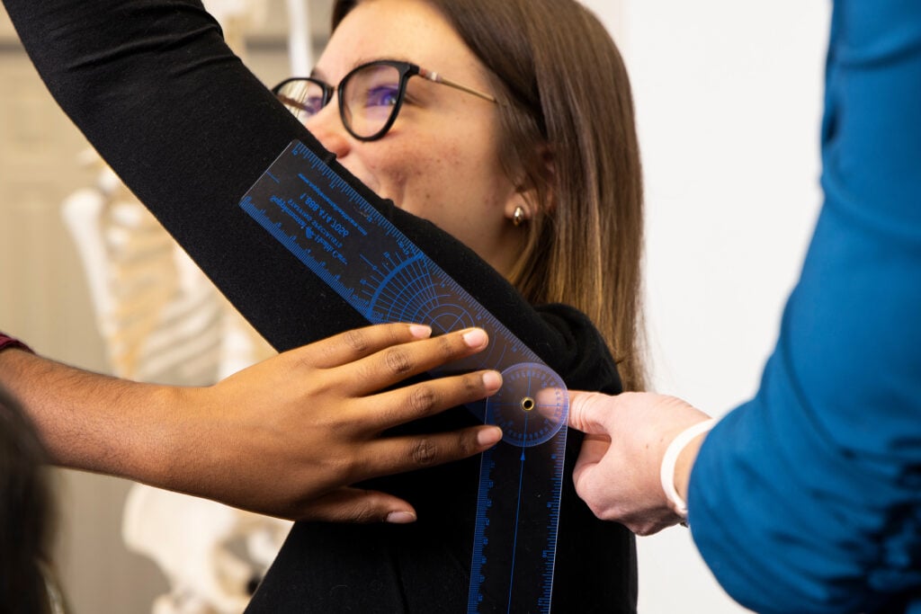 An occupational therapy student’s shoulder range of motion is measured with a goniometer during a hands-on laboratory activity.