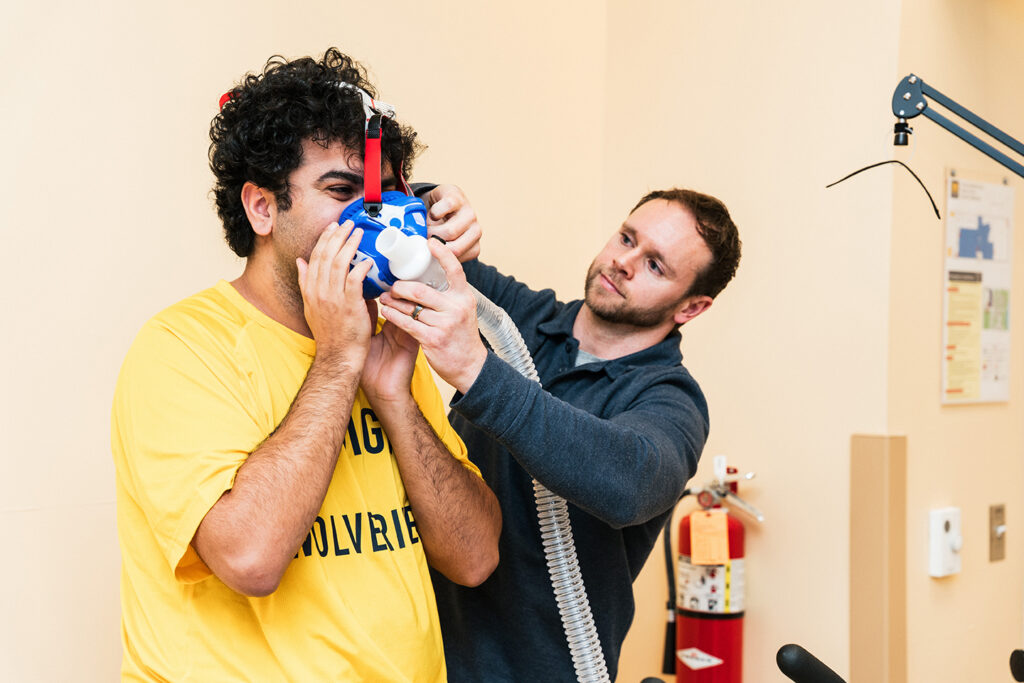 An instructor adjusts a respiratory testing mask on a UM-Flint exercise science student during a laboratory assessment.