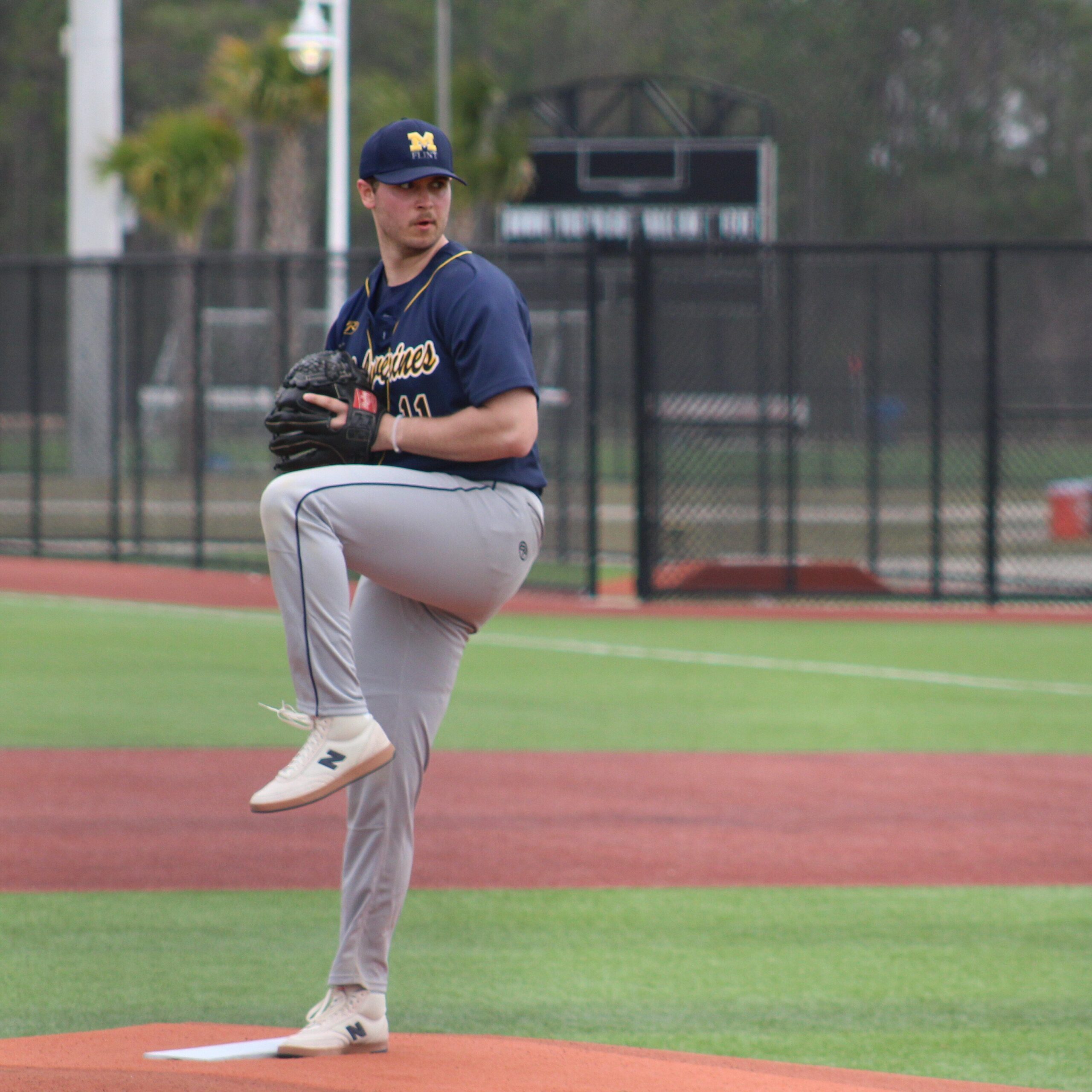 A person in a baseball uniform is on the pitcher's mound, preparing to throw a pitch.