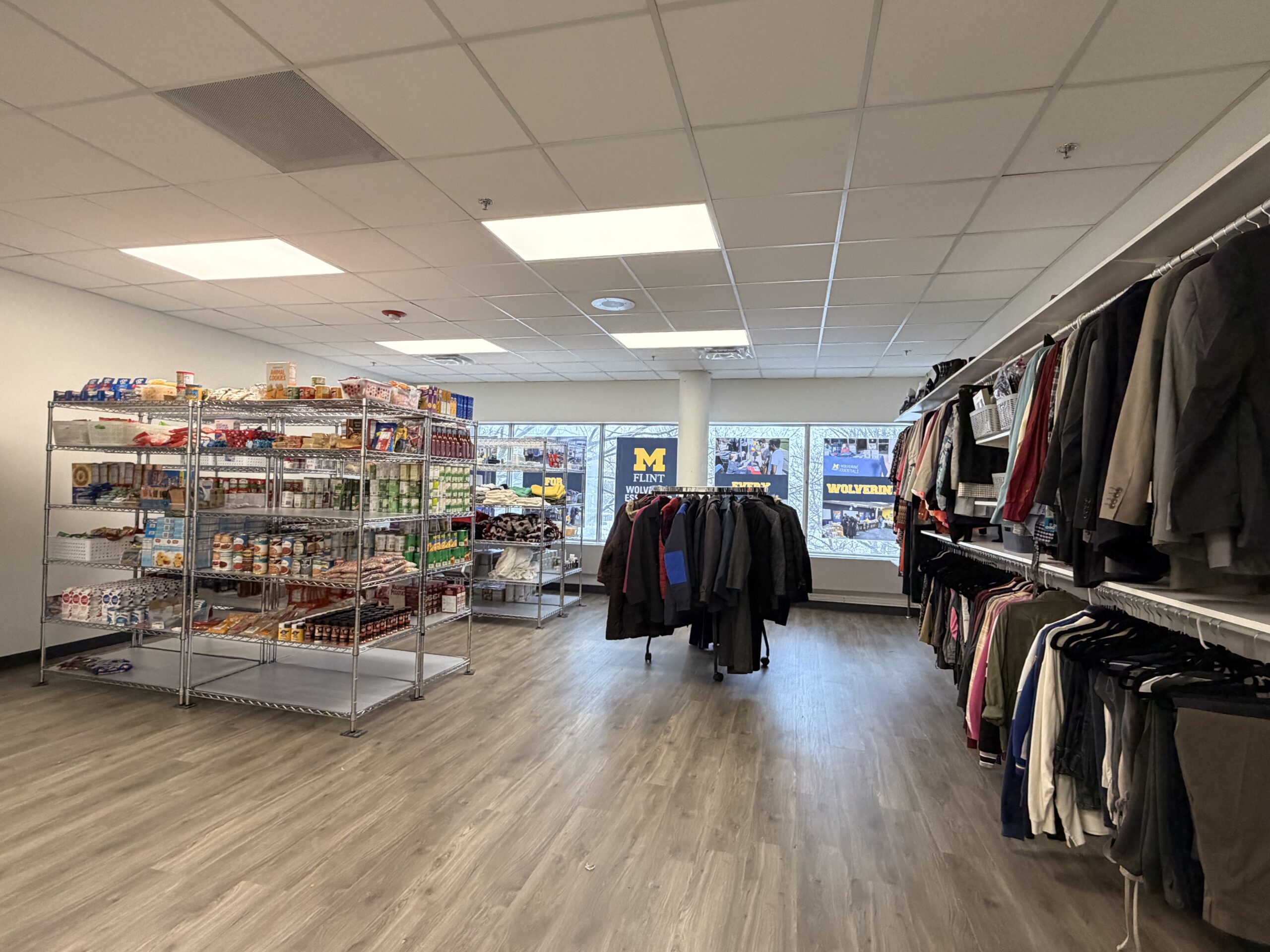 An interior view of Wolverine Essentials featuring shelves stocked with food items on one side and clothing racks on the other.