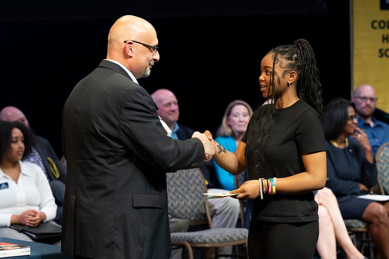 Vice Chancellor Christopher Giordano shaking hands with a student at a scholarship ceremony.
