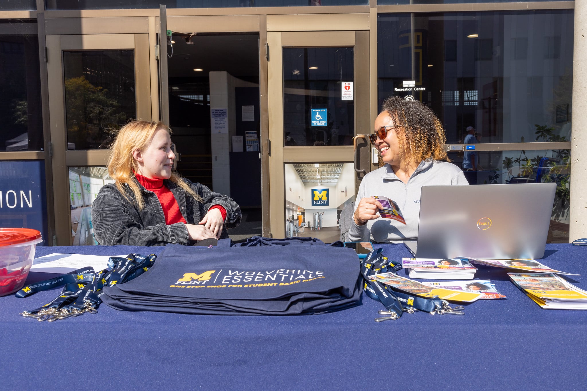 Wolverine Essentials table with tote bags and information at a campus event.