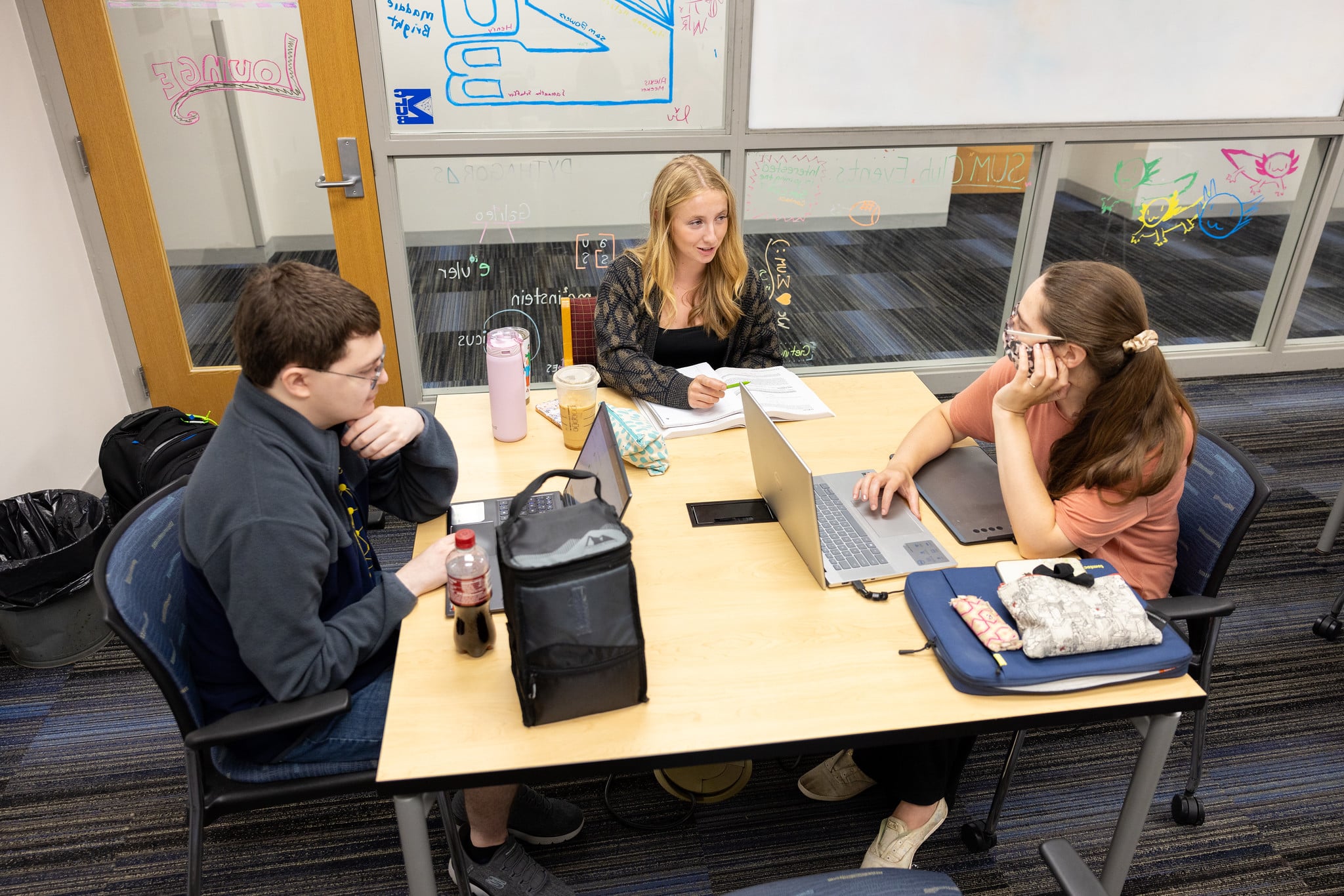 UM-Flint students studying with laptops open on a square table