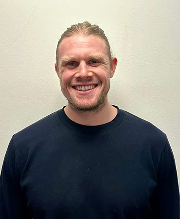 Gunnar Lundteigen smiling in a black long-sleeve shirt against a plain background.