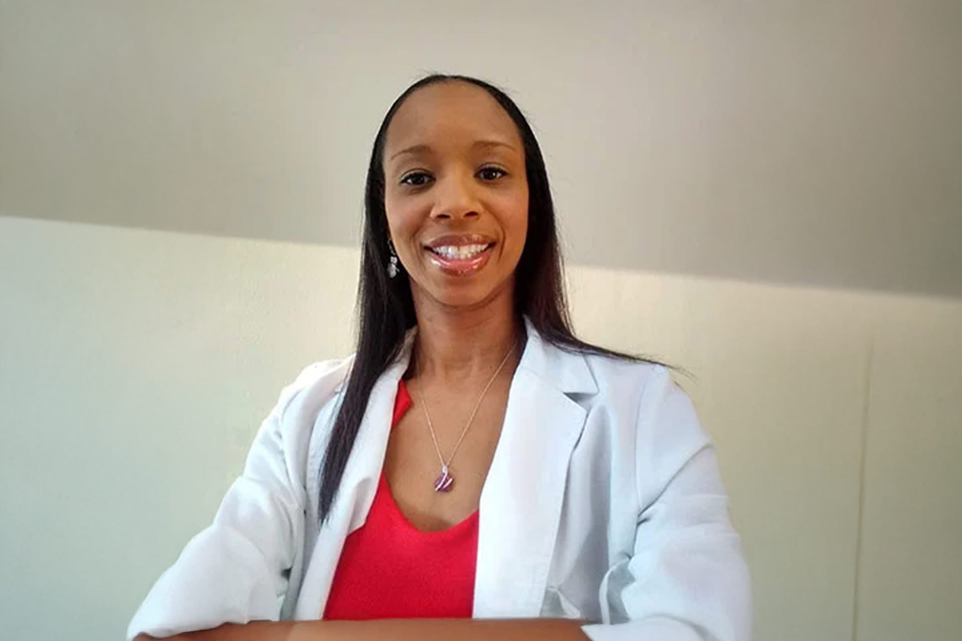 Kimberly Snodgrass in a white lab coat smiles while standing with arms crossed, against a light background.