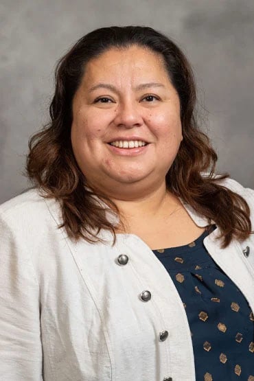 Jania Torreblanca smiling in a professional setting, wearing a light-colored jacket over a dark polka-dotted top.