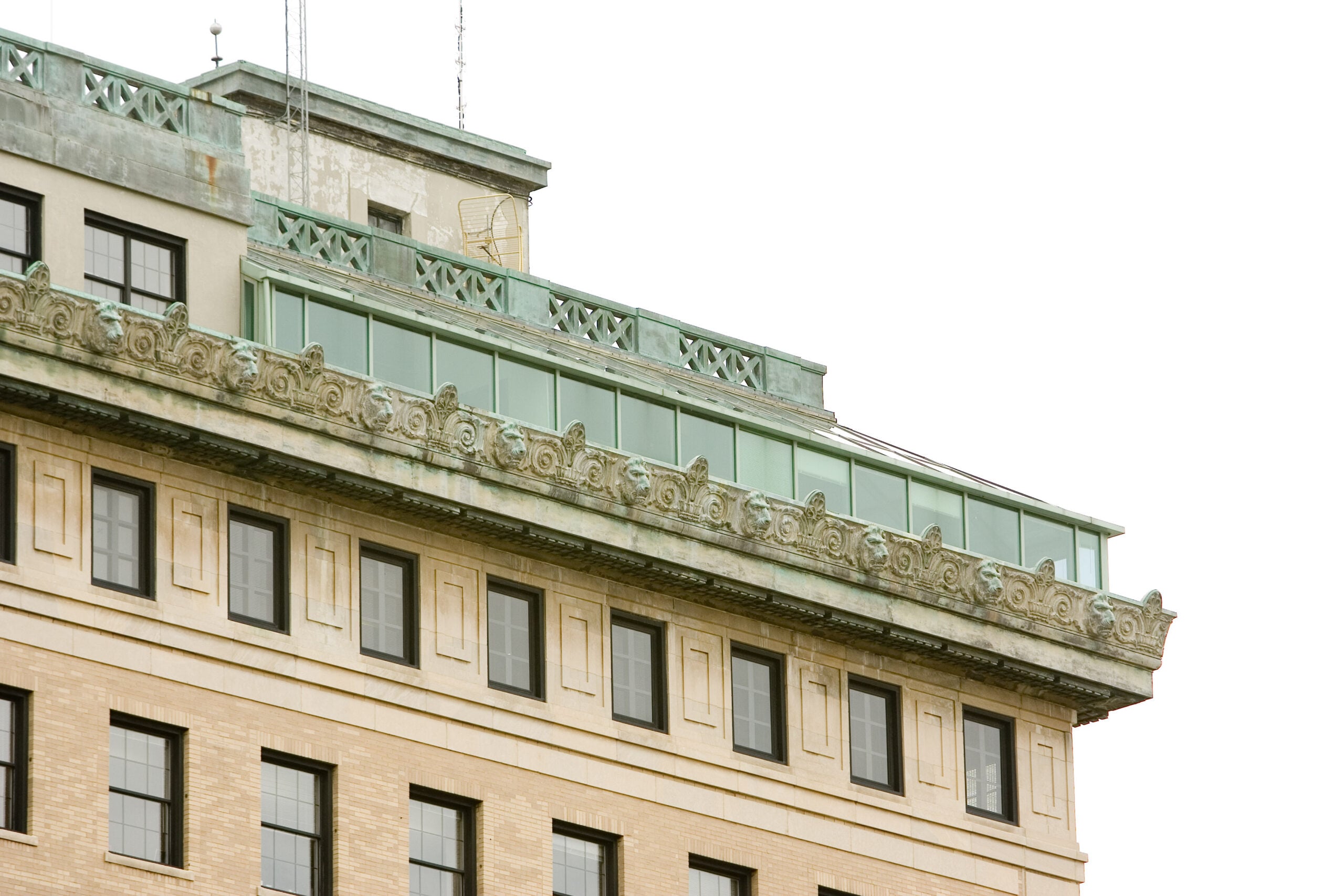 A close-up view of the upper section of a building featuring decorative architectural details and a glass balcony.