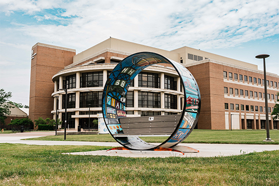 large circular artpiece outside of a large building with many windows