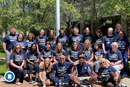 Group photo of people wearing matching navy blue shirts that say "Future Nurse Summer Camp" outdoors with trees and a building in the background.
