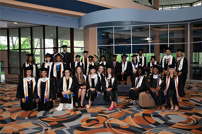 Genesee Early College graduates posing together in caps and gowns at commencement.