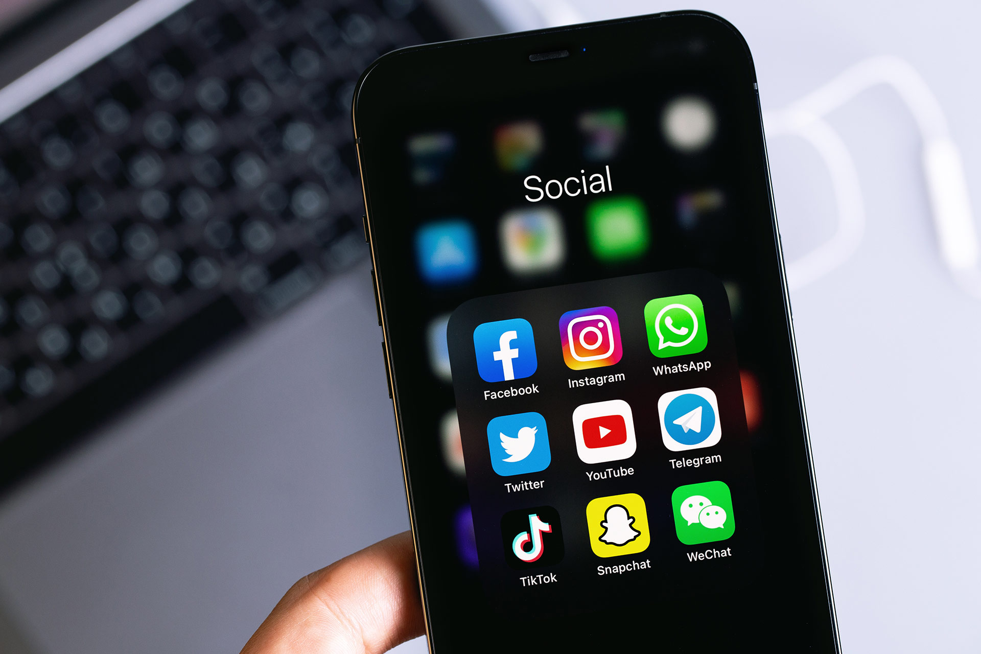 A smartphone displaying a folder labeled "Social" with icons for various social media apps, including Facebook, Instagram, WhatsApp, X, YouTube, Telegram, TikTok, Snapchat, and WeChat.