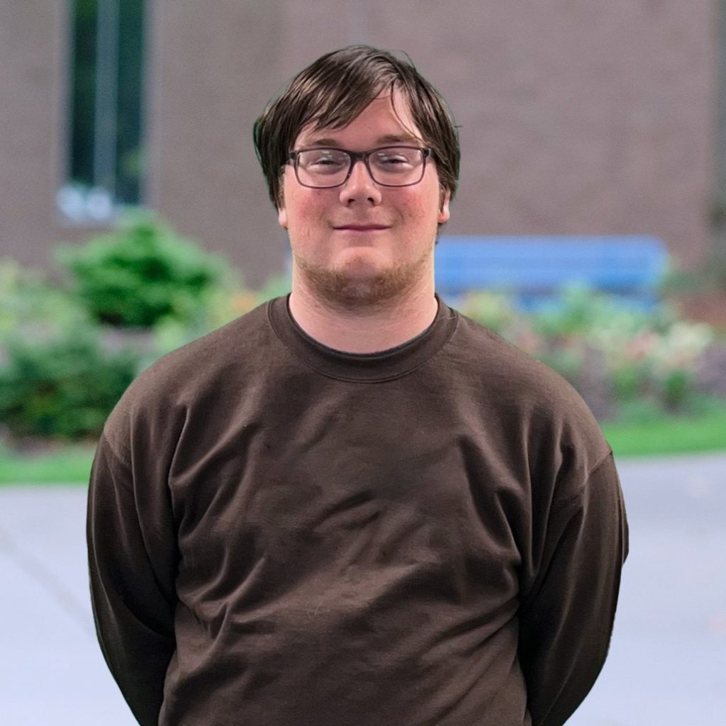 Young man with brown hair and glasses in a brown crewneck