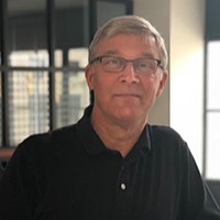 Man with gray hair and glasses in a black polo