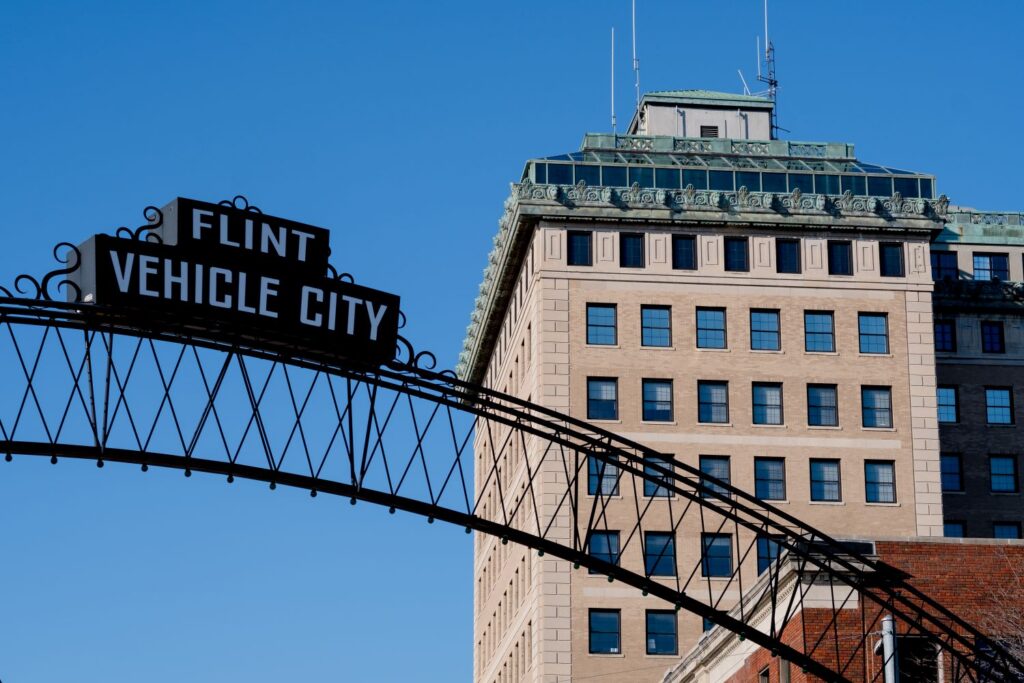 Flint Vehicle City sign with the Northbank Center building behind it