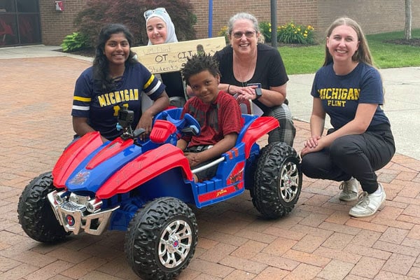 Four woman around a young child in a toy car