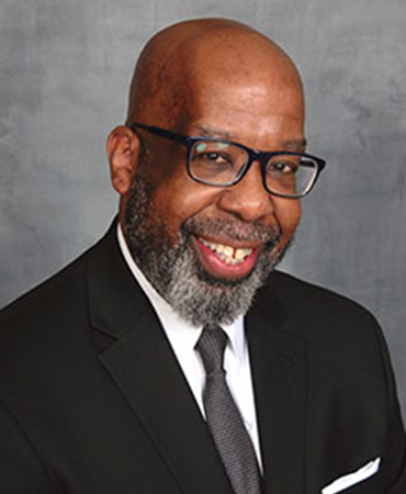 African American man in a black suit with glasses