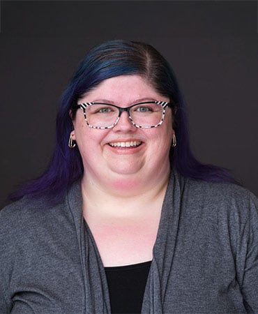 Woman with blue and purple hair and black and white glasses