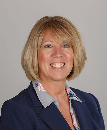 Potrait of a woman with short blonde hair in a navy blazer