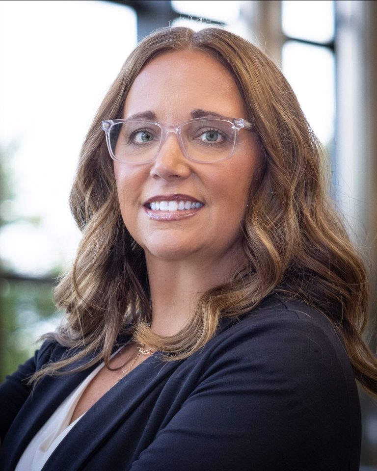 Portrait of a woman with curled brown hair and glasses