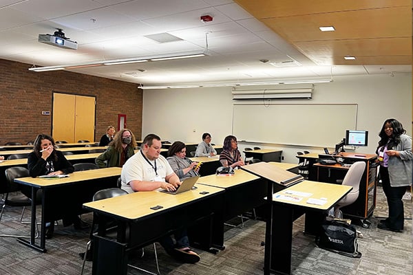 a small group of people at tables in a classroom