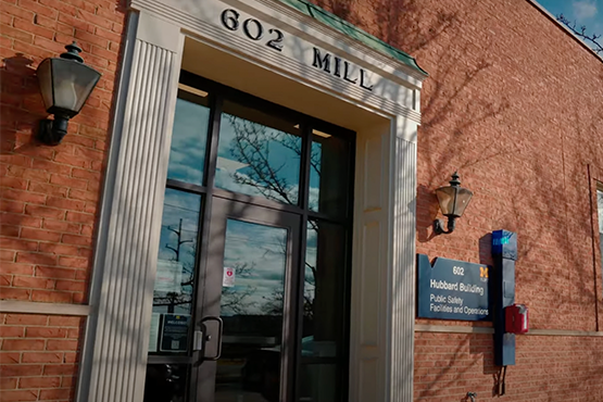 Entrance of the Hubbard Building at 602 Mill Street, home of Public Safety, Facilities and Operations, with a blue emergency phone beside the door.
