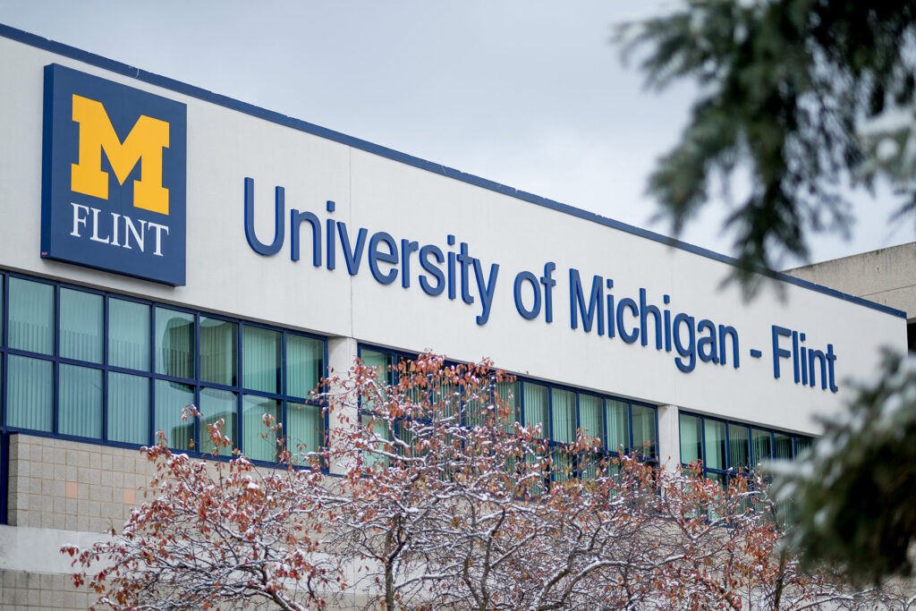 Signage for the University of Michigan - Flint, featuring a large "M" logo and the name of the institution.
