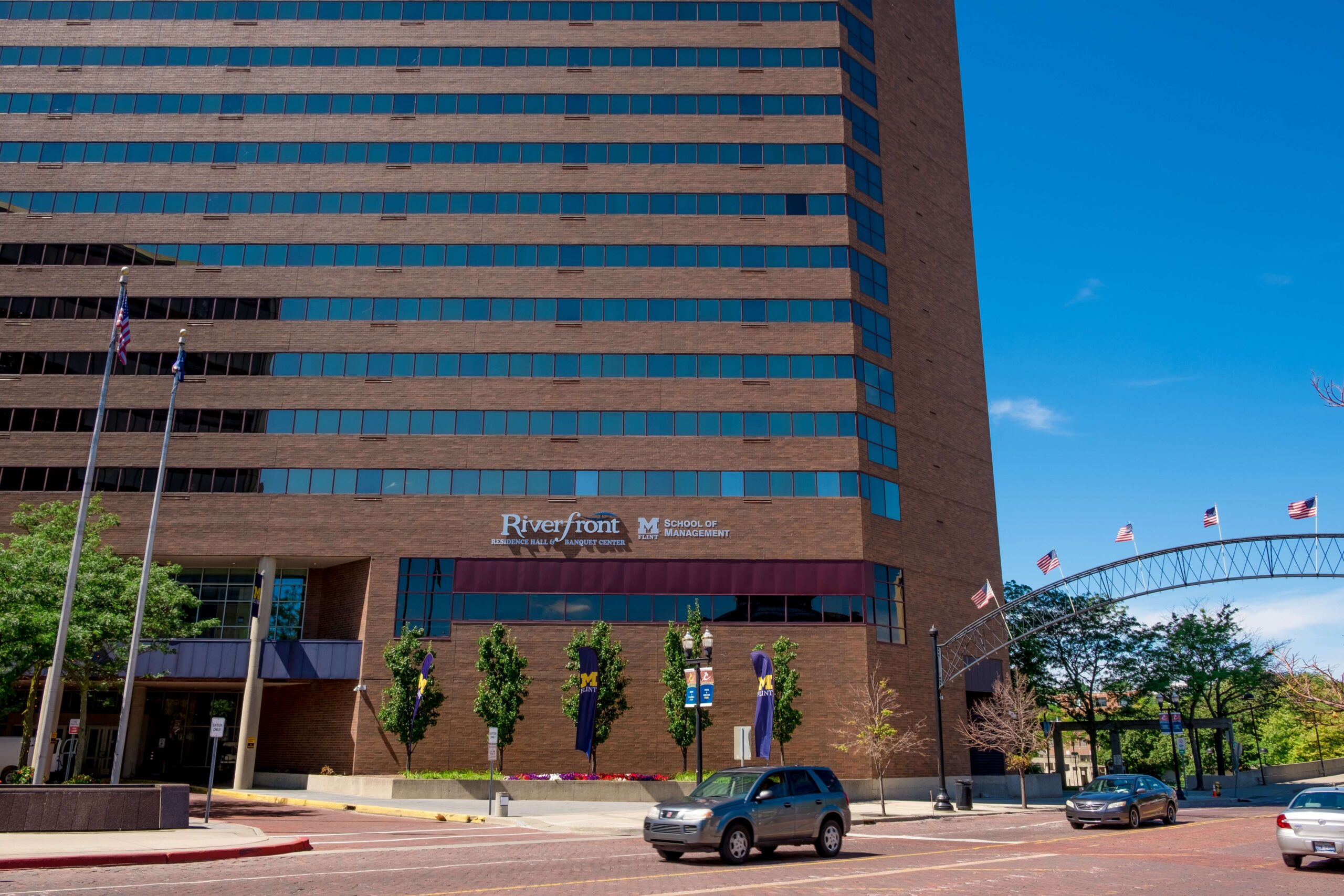 A tall brick office building with a modern design sits within view of a clear blue sky. The building has horizontal rows of reflective windows.