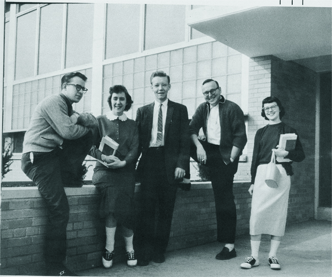 Students and staff greeting each other at a counter on the first day of classes, 1956.