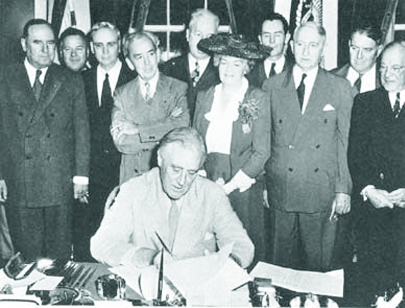 President Franklin D. Roosevelt signing the GI Bill, surrounded by officials.