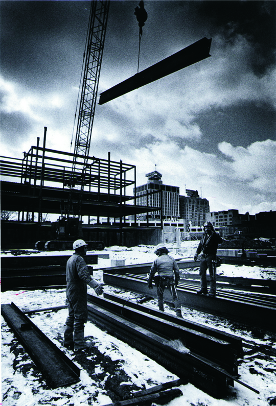 Construction workers and a crane at the Classroom Office Building construction site.