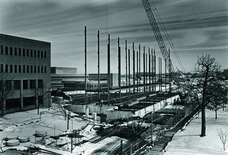 Construction site for the Murchie Science Building, with tall scaffolding and downtown Flint in the background.