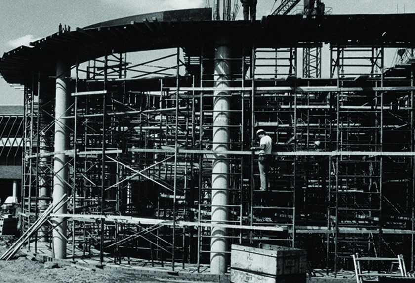 Construction of the Frances Willson Thompson Library, with scaffolding around a circular structure.