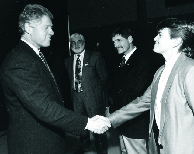 President Bill Clinton shaking hands with university officials during a campus visit.