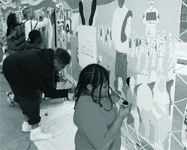 Students and community members gathered around a mural-covered wall at a 9/11 memorial event.